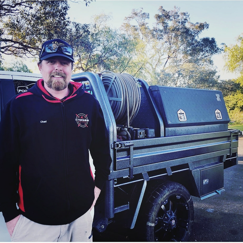 Chad from X-TERMIN8 standing beside his pest control ute and spray rig