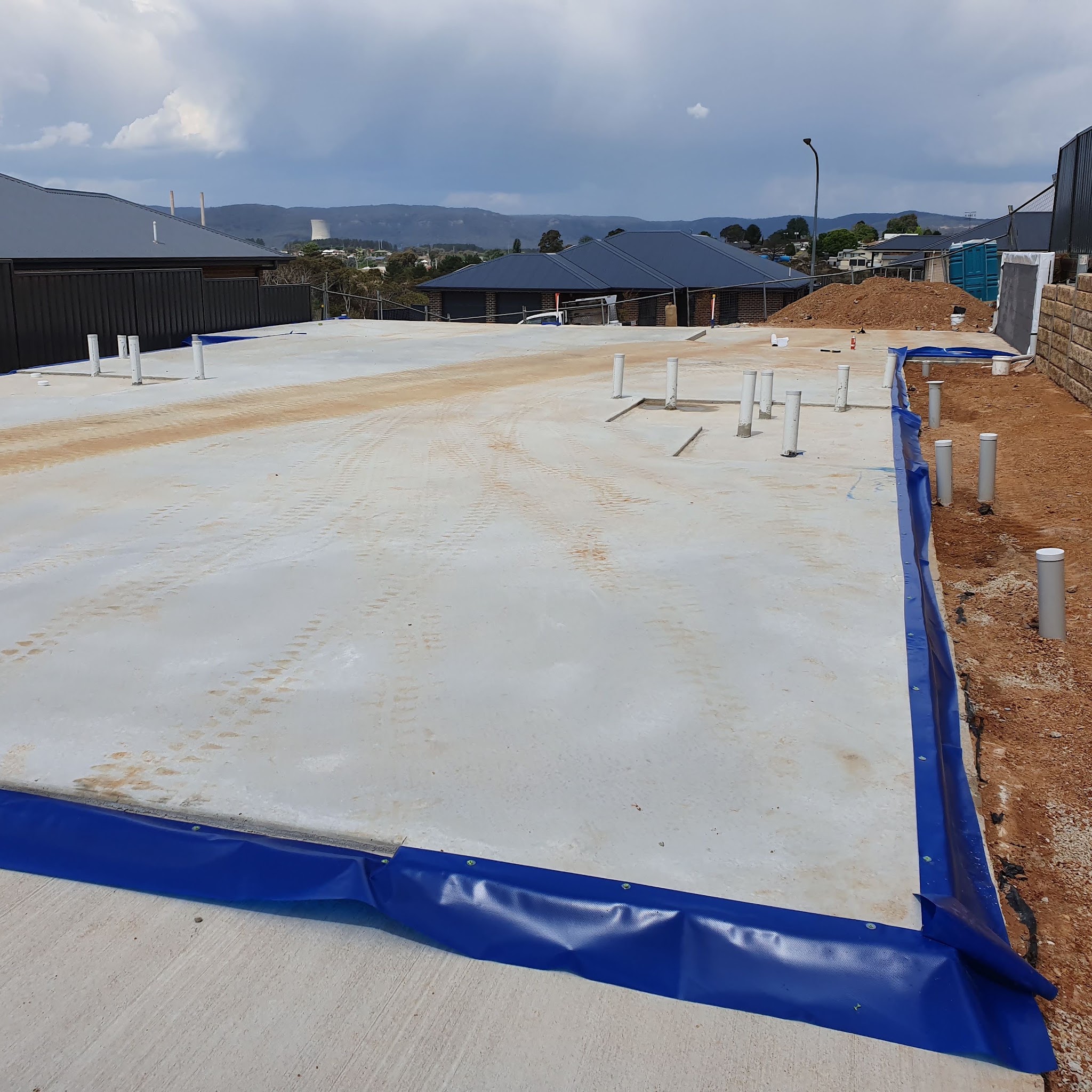 New concrete house slab with blue termite barrier fitted around its perimeter